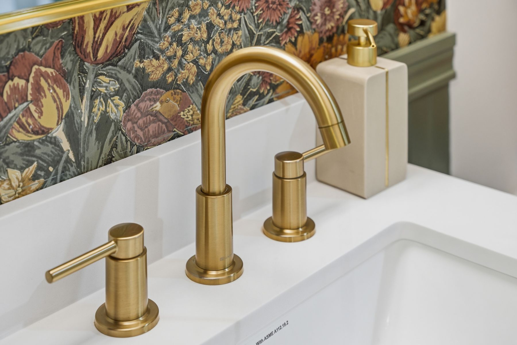 Brass faucet against floral wallpaper