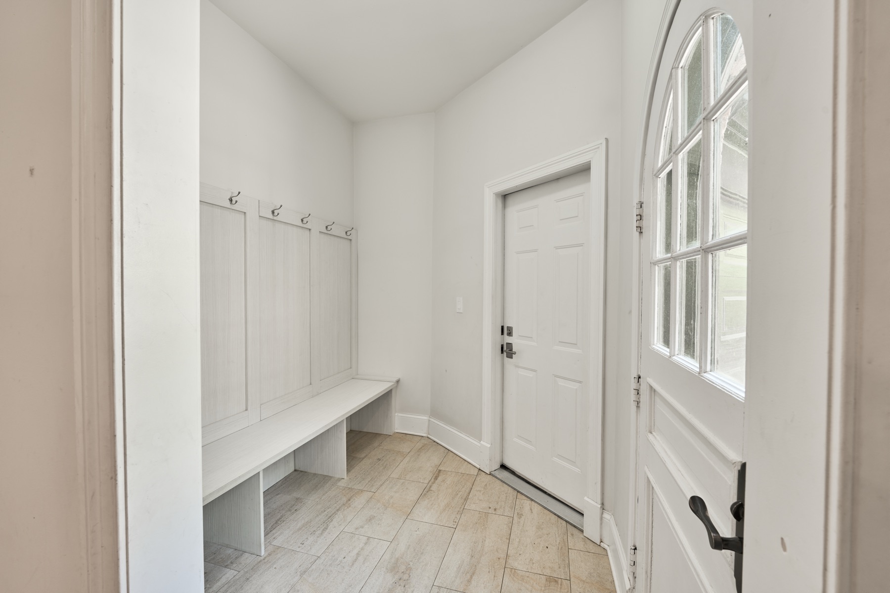 Mudroom with built-in bench and arched window